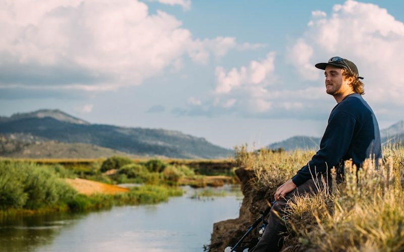 man in blue sweater sitting on rock during daytime